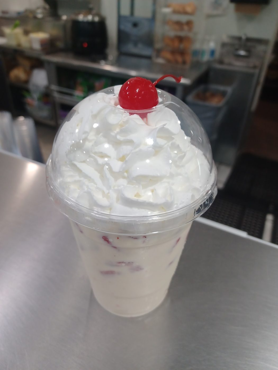 A cup of ice cream topped with whipped cream and a cherry.