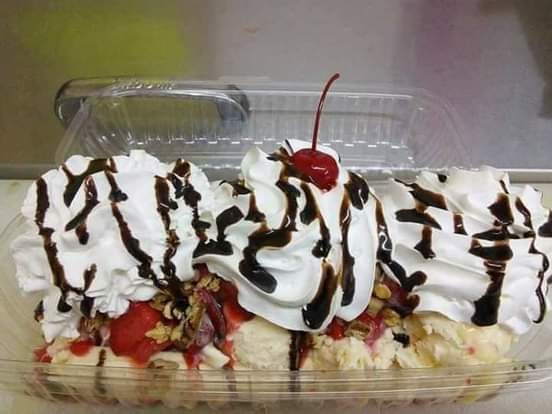 A banana split sundae with whipped cream, chocolate drizzle and a cherry.